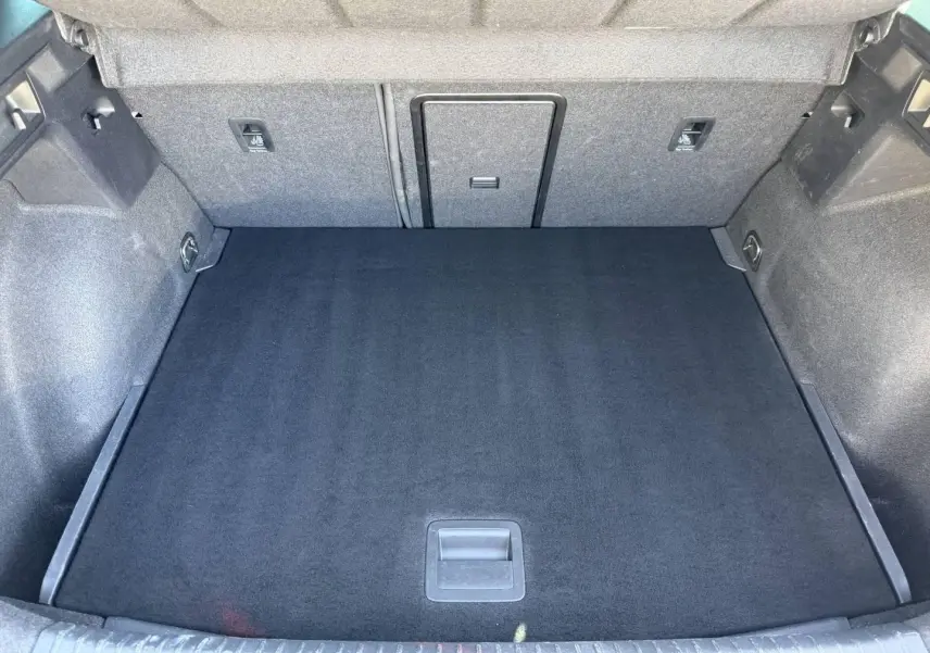 Vue plongeante sur le coffre spacieux et propre du CUPRA Formentor gris magnétique, avec revêtement noir et rangements intégrés.