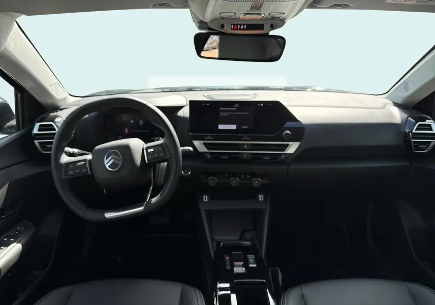 Vue intérieure avant du poste de conduite noir de la Citroën C4 X avec écran tactile et volant multifonctions.