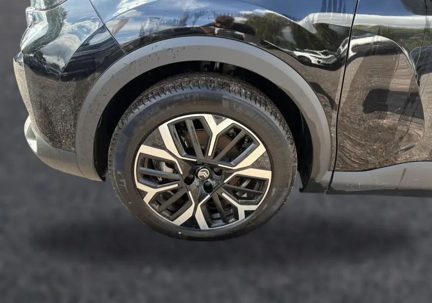Gros plan sur la roue avant gauche noire d'une Citroën C4 X 2025 avec jante alu au design moderne.