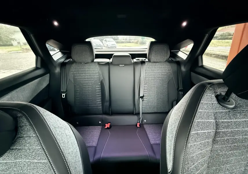 Vue intérieure arrière du Peugeot 3008 Hybrid 136ch Allure 2025, sièges tissu gris et cuir noir contrasté.
