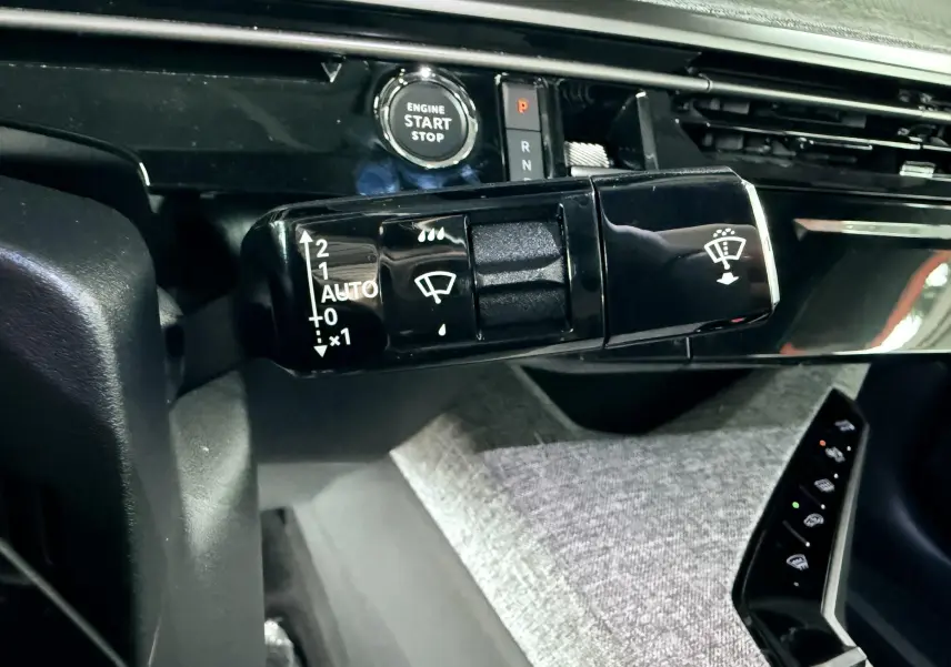 Gros plan sur la commande d'essuie-glace et le bouton start/stop du tableau de bord du Peugeot 3008 Hybrid 2025.