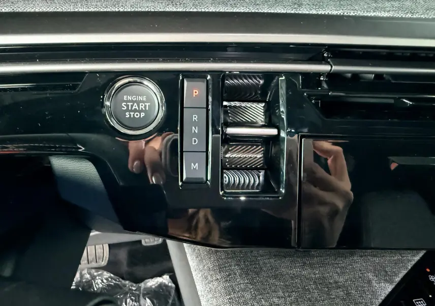 Détail de la console centrale noire brillante du Peugeot 3008 Hybrid 2025 avec bouton start/stop et commandes de boîte automatique.