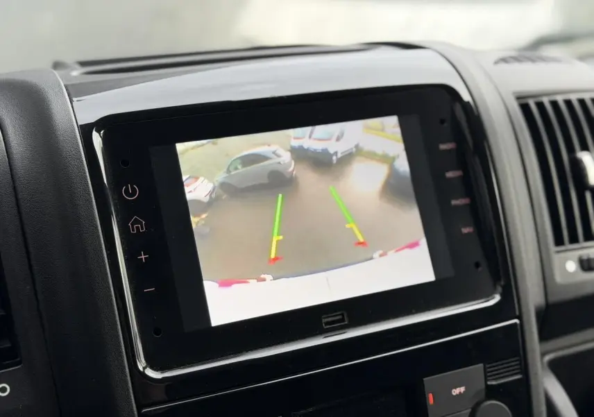 Écran tactile du système multimédia montrant la caméra de recul du fourgon Opel Movano blanc, vue intérieure avant.