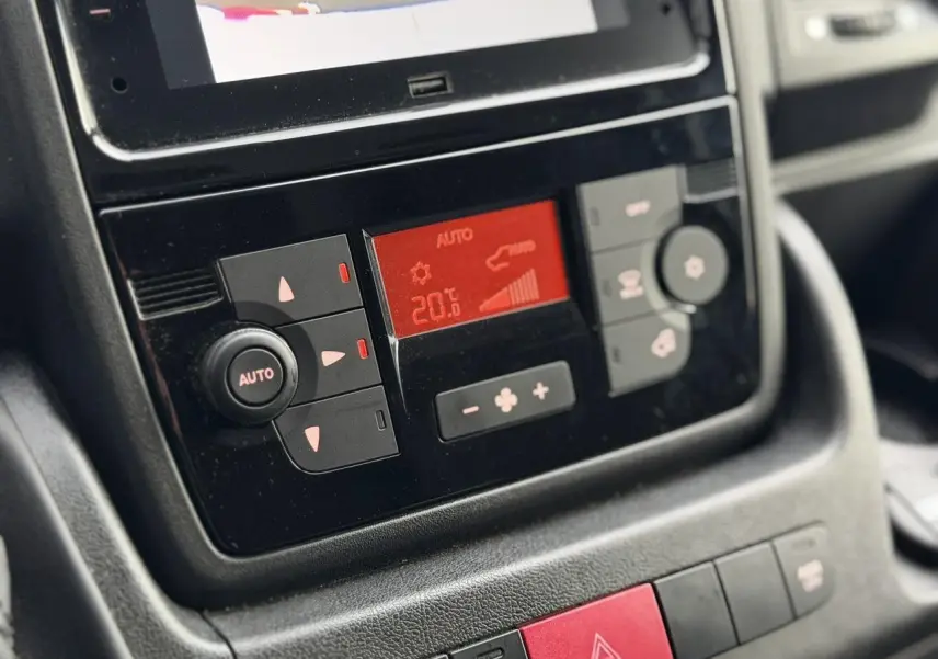 Gros plan sur la console centrale noire du Opel Movano Fourgon 2024, affichant la climatisation automatique à 20°C.