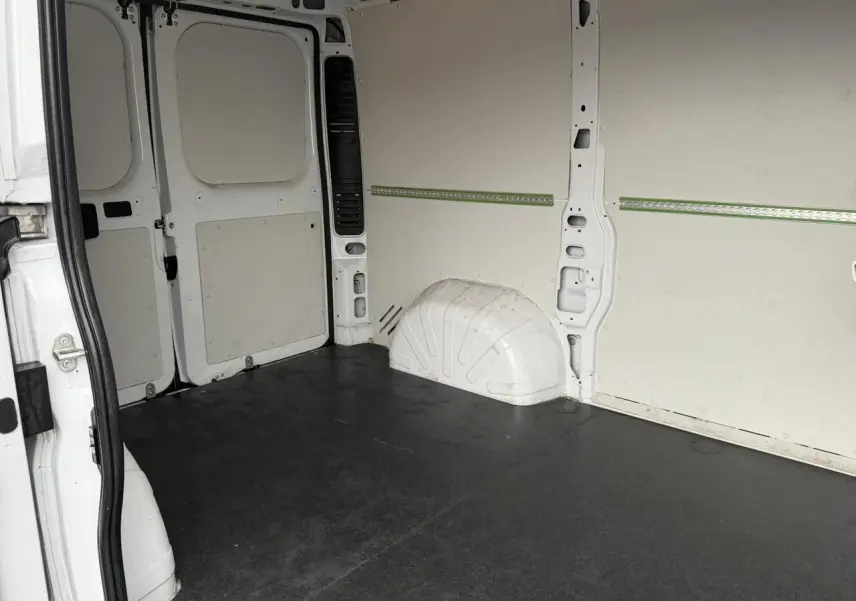 Vue intérieure arrière du fourgon blanc Opel Movano L1H1, montrant le plancher bois et les parois tôlées.