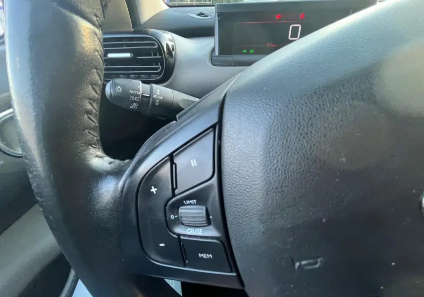 Gros plan sur le volant noir de la Citroën C4 Cactus 2020 avec commandes intégrées et tableau de bord digital en arrière-plan.