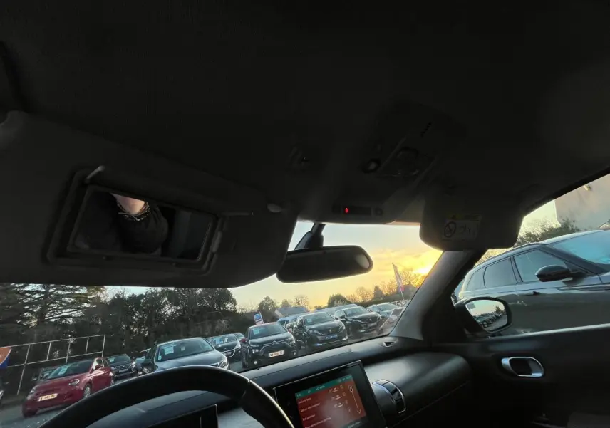 Vue intérieure du poste de conduite du Citroën C4 Cactus 2020, avec tableau de bord et écran tactile visible au coucher du soleil.