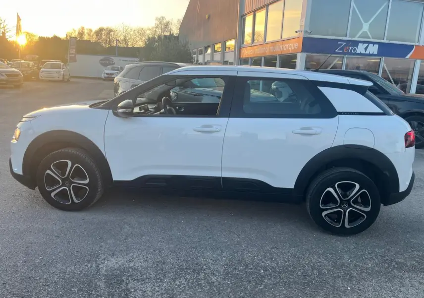 Vue de profil côté gauche d'une Citroën C4 Cactus blanche de 2020 avec jantes noires et détails noirs contrastants.