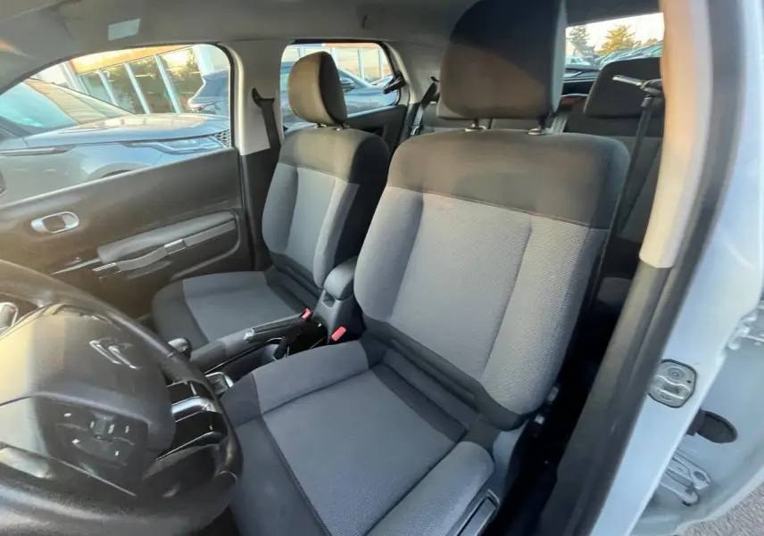 Vue intérieure côté conducteur du Citroën C4 Cactus blanc 2020, montrant les sièges avant en tissu gris et noir.