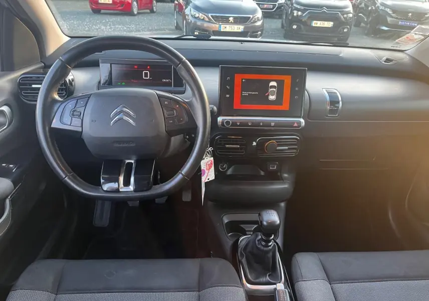Vue intérieure avant du Citroën C4 Cactus 2020 diesel blanc, volant multifonction et écran tactile central allumé.