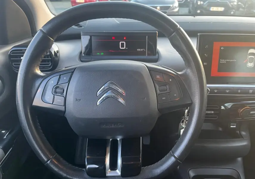 Vue rapprochée du volant noir de la Citroën C4 Cactus 2020 avec tableau de bord digital et écran tactile central allumé.