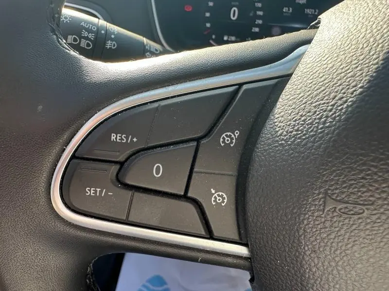 Gros plan sur les commandes du régulateur de vitesse au volant d’une Renault Mégane Break gris Titanium 2024.