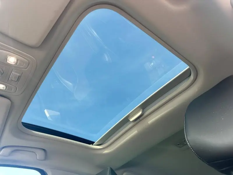 Toit ouvrant panoramique vu de l'intérieur d'une Renault Mégane Break gris Titanium, ciel bleu visible à travers.