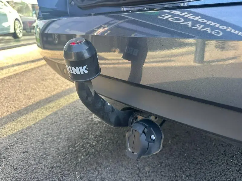 Gros plan sur l'attelage de remorque avec cache noir marqué "BRINK" sur le pare-chocs arrière gris titanium d'une Renault Mégane Break.