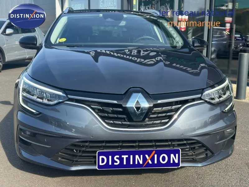 Vue avant rapprochée de la Renault Mégane Break 2024 gris Titanium avec calandre chromée et phares LED allumés.