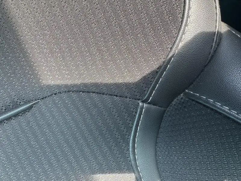 Gros plan sur le revêtement mixte similicuir et tissu noir d’un siège avant de Renault Mégane Break Gris Titanium 2024.