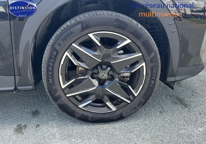 Gros plan sur la roue avant gauche noire du Peugeot 5008 Hybrid 145 allure e-dcs6 avec jante alu distinctive.
