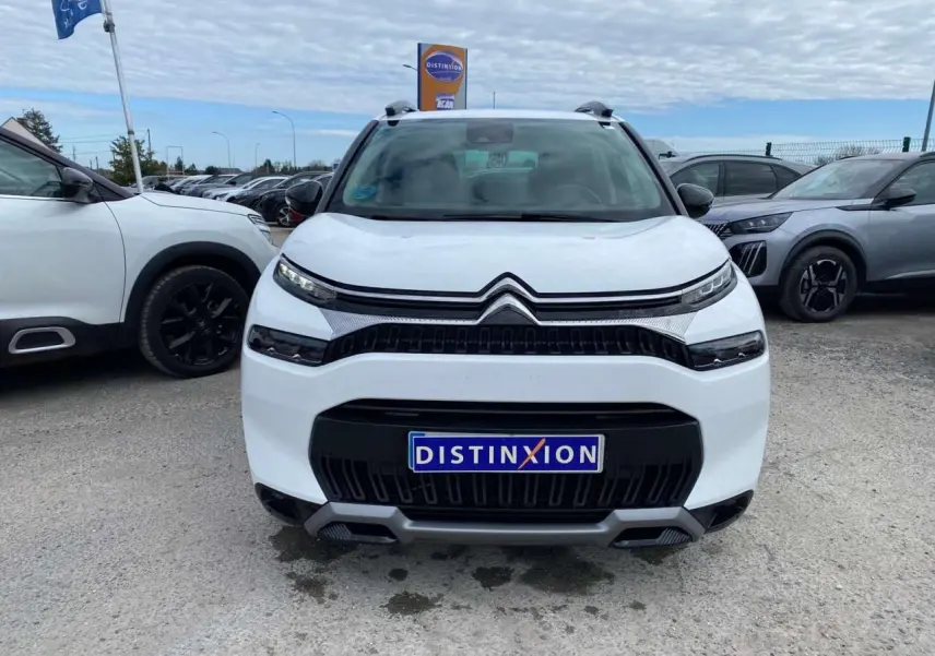 Vue avant d'un Citroën C3 Aircross blanc 2023 avec calandre noire et détails gris, sur parking extérieur.