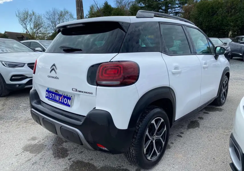 Vue 3/4 arrière droite d'un Citroën C3 Aircross blanc 2023 avec toit noir et jantes alliage distinctives.