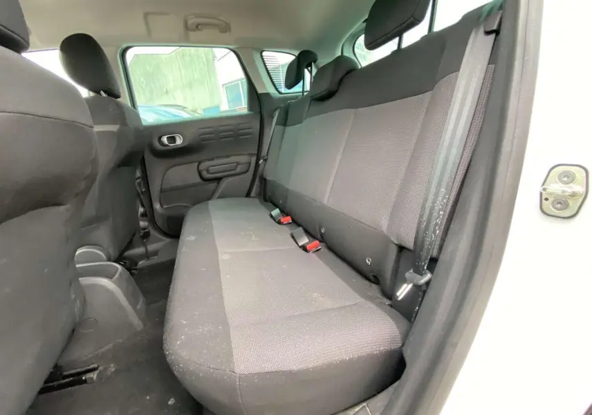 Vue intérieure côté droit sur la banquette arrière noire du Citroën C3 Aircross blanc, porte arrière ouverte.