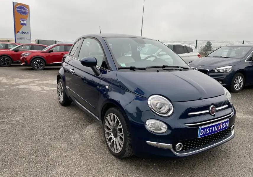 Vue 3/4 avant droite d'une Fiat 500 bleu foncé avec toit panoramique, sur parking de concession.