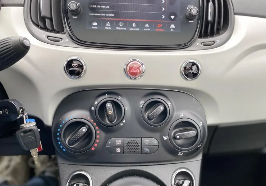 Vue rapprochée du tableau de bord beige clair de la Fiat 500 2019 avec commandes climatisation et écran tactile.