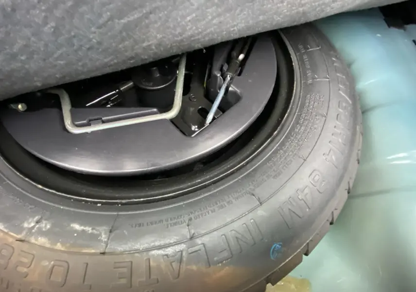 Gros plan sur la roue de secours et les outils dans le coffre d'une Fiat 500 2019, couleur INC.