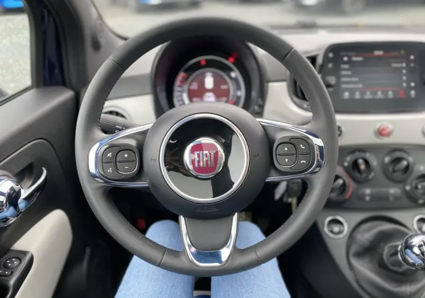 Vue intérieure centrée sur le volant noir et chrome du Fiat 500 2019 avec tableau de bord et levier de vitesses manuel visibles.