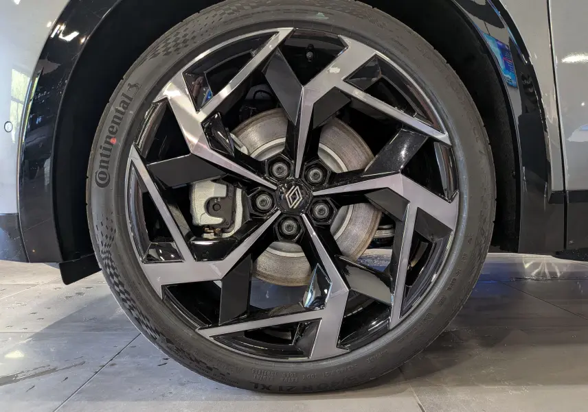 Gros plan sur la roue avant droite du Renault Rafale gris schiste, mettant en valeur la jante noire et argentée au design géométrique.