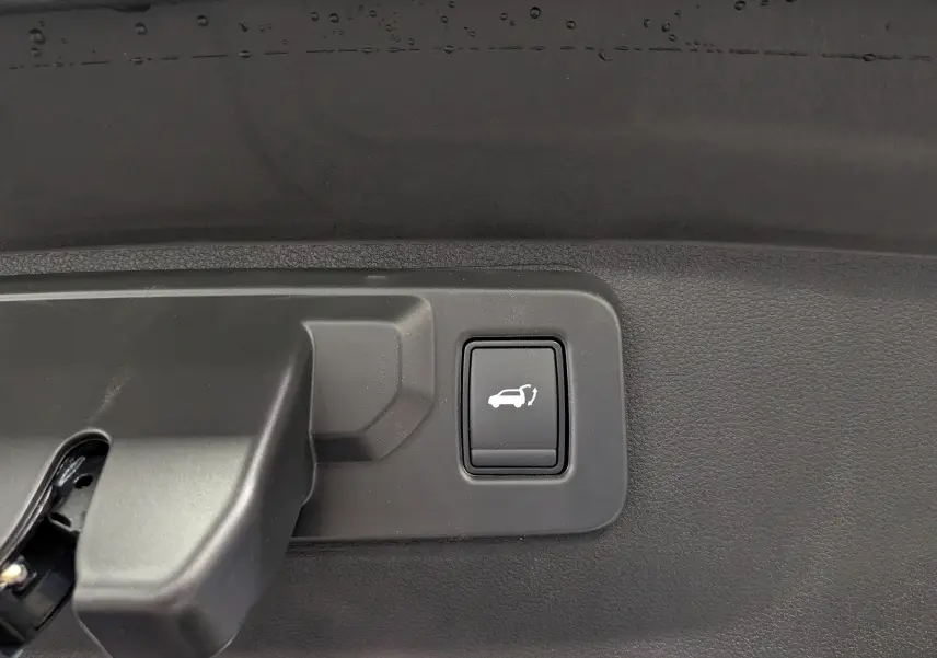 Bouton d'ouverture électrique du hayon sur la garniture intérieure du coffre d'une Renault Rafale gris schiste.