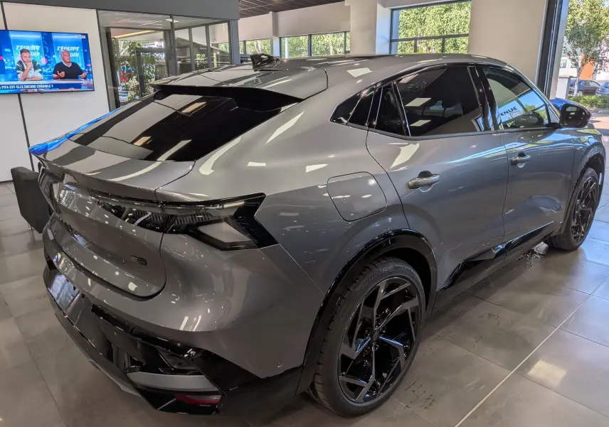 Vue 3/4 arrière droite d’un Renault Rafale gris schiste avec jantes noires et toit noir brillant en showroom.
