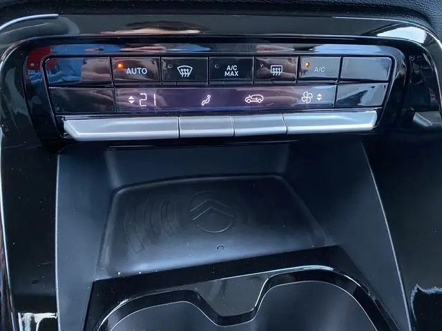 Détail du panneau de climatisation et recharge sans fil avec logo Citroën, intérieur noir du C3 Aircross 2025 hybride.