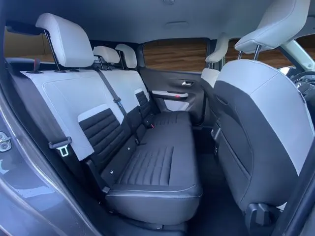 Vue intérieure arrière droite du Citroën C3 Aircross 2025 gris Mercury, sièges tissu noir et blanc, 7 places visibles.
