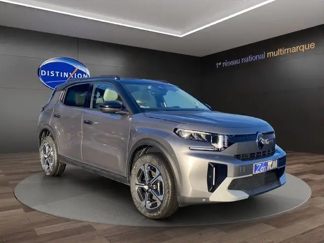 Vue 3/4 avant d'un Citroën C3 Aircross hybride gris Mercury avec toit noir, roues distinctives et calandre moderne.