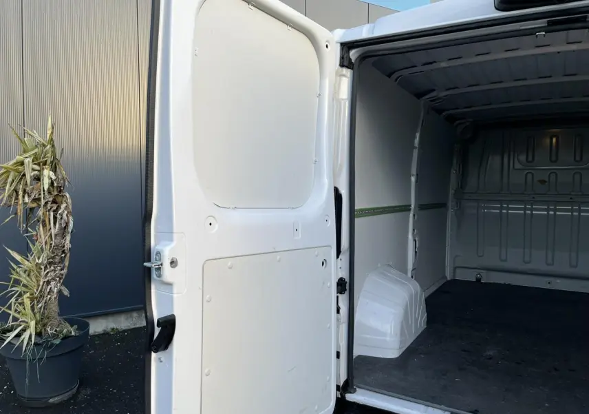 Vue arrière droite du fourgon blanc Opel Movano 2024 avec porte latérale ouverte montrant l'intérieur vide et plancher noir.