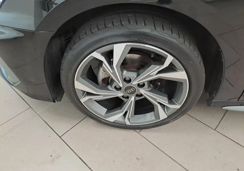 Gros plan sur la roue avant gauche de l’Audi A3 Sportback Noir Mythic avec jante alliage S Line 2023.