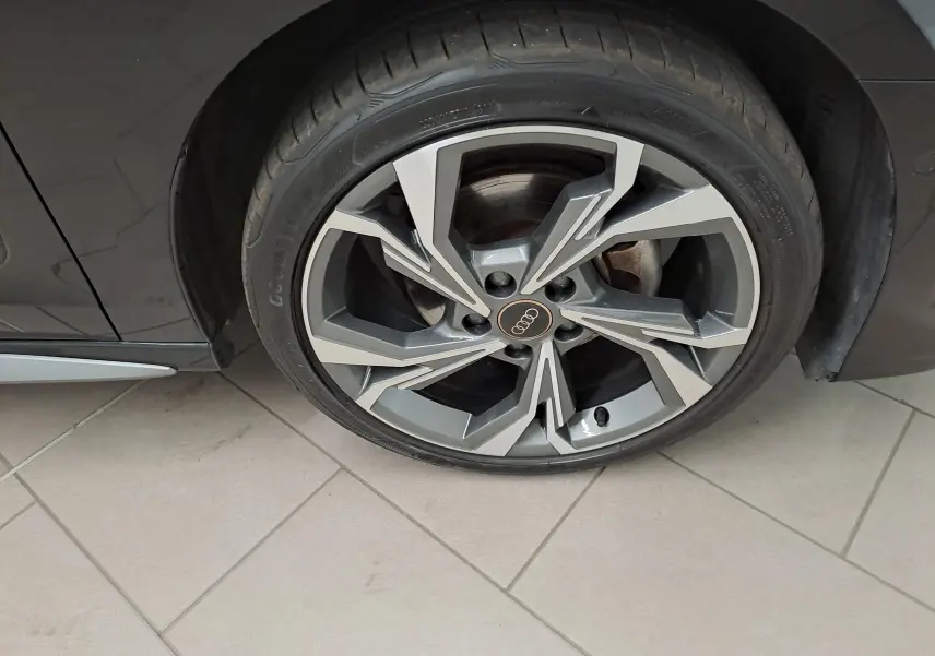 Gros plan sur la roue avant droite d’une Audi A3 Sportback 35 TFSI S Line noire mythic avec jante alliage au design géométrique.