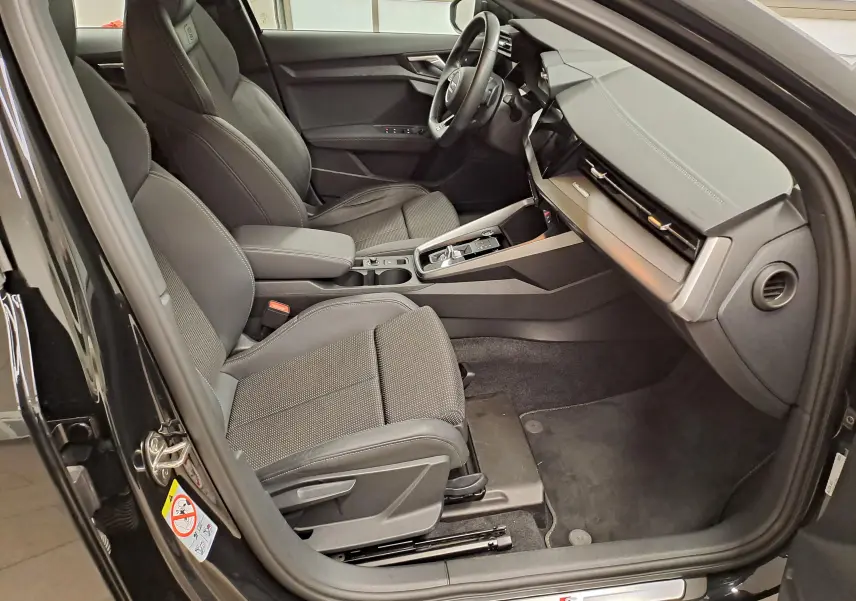 Vue intérieure côté conducteur de l'Audi A3 Sportback 35 TFSI S Line 2023 en Noir Mythic, avec sièges sport et tableau de bord moderne.