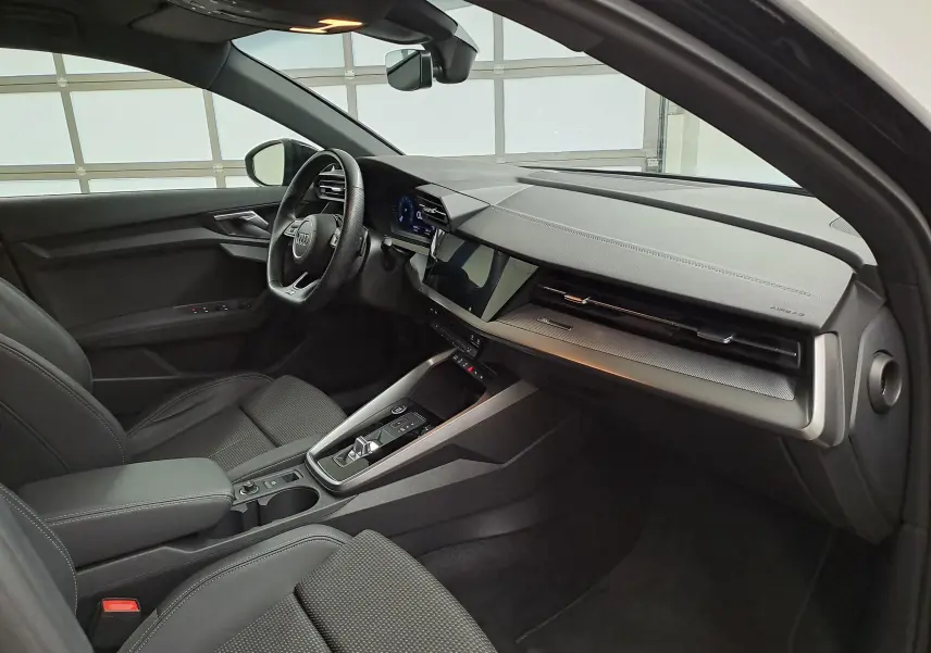 Vue intérieure côté conducteur de l'Audi A3 Sportback 35 TFSI S Line 2023 en Noir Mythic, avec tableau de bord moderne et écran tactile.