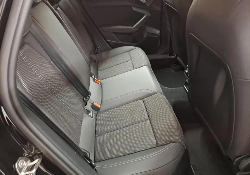 Vue intérieure côté arrière droit montrant les sièges arrière en tissu et cuir noir de l'Audi A3 Sportback 2023 S Line.