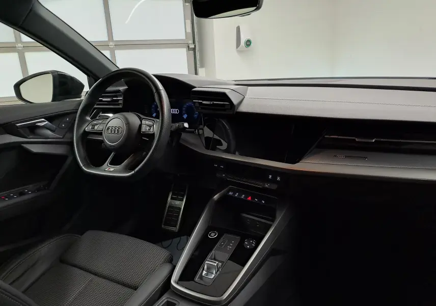 Intérieur noir de l'Audi A3 Sportback 35 TFSI 150 S Line 2023, vue côté conducteur sur le tableau de bord et volant.