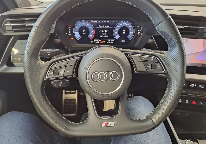 Vue intérieure centrée sur le volant S Line noir perforé de l'Audi A3 Sportback 35 TFSI 2023 avec tableau de bord numérique.