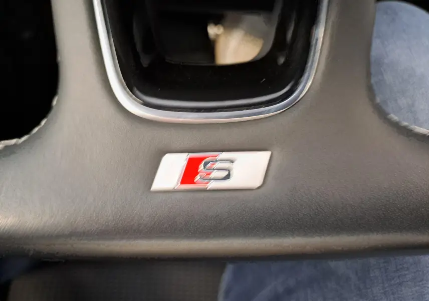 Gros plan sur le logo S Line rouge et argenté sur la console centrale noire de l’Audi A3 Sportback 35 TFSI 2023.