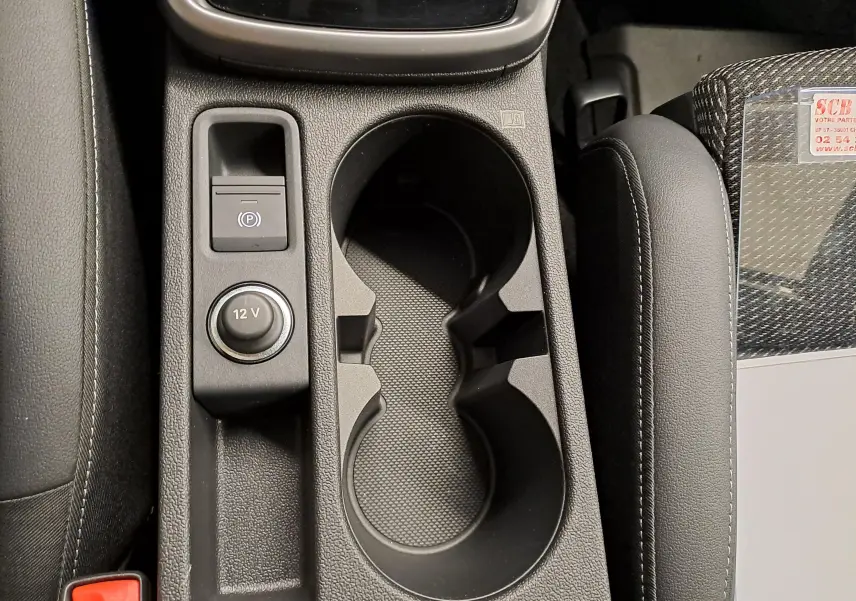 Gros plan sur la console centrale de l’Audi A3 Sportback 35 TFSI S Line 2023, avec porte-gobelets et bouton 12V.