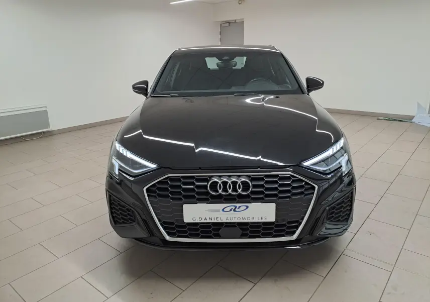 Audi A3 Sportback 35 TFSI S Line noir mythic vue de face en intérieur avec calandre hexagonale et phares LED distinctifs.