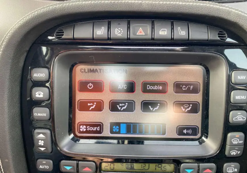 Gros plan sur l'écran tactile du centre multimédia de la Jaguar XJ noire, affichant les commandes de climatisation.