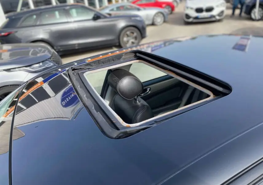 Toit ouvrant ouvert vu de dessus sur une Jaguar XJ noire, avec appui-tête avant visible à l'intérieur.