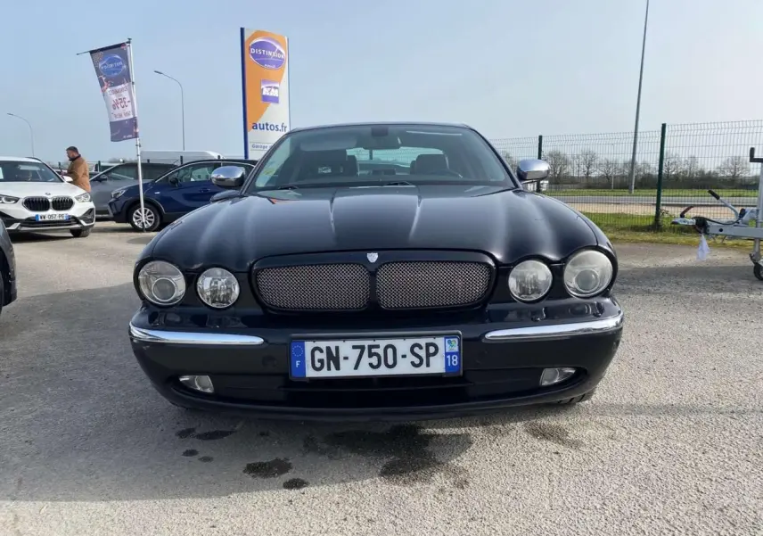Vue avant d'une Jaguar XJ noire de 2006 avec calandre chromée et phares ronds, stationnée en extérieur.