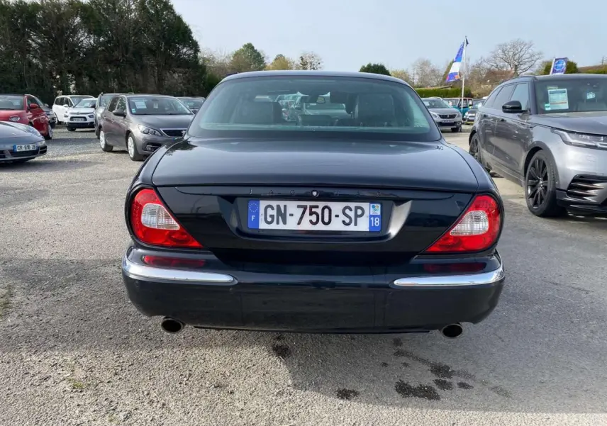 Vue arrière d'une Jaguar XJ noire de 2006, avec feux rouges caractéristiques et double sortie d'échappement visible.