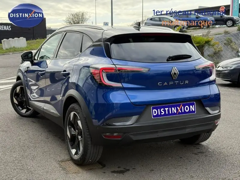 Vue 3/4 arrière d'un Renault Captur 2025 Bleu Iron/Noir Étoilé avec vitres teintées et jantes noires distinctives.